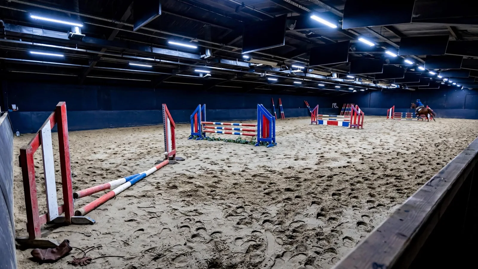 Indoor jumper course with coloured rails and one rail knocked to the ground